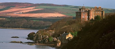 A castle on a hill overlooking a body of water.