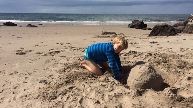 A child playing on a sandy beach with rocks and the ocean in the background. - Sunny south facing Riverside home  (Ayr)
