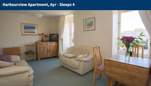 A Harbourview apartment with a sofa, a wooden table, a TV, and a window with a view. - Harbourview Apartment, Ayr (Ayr)