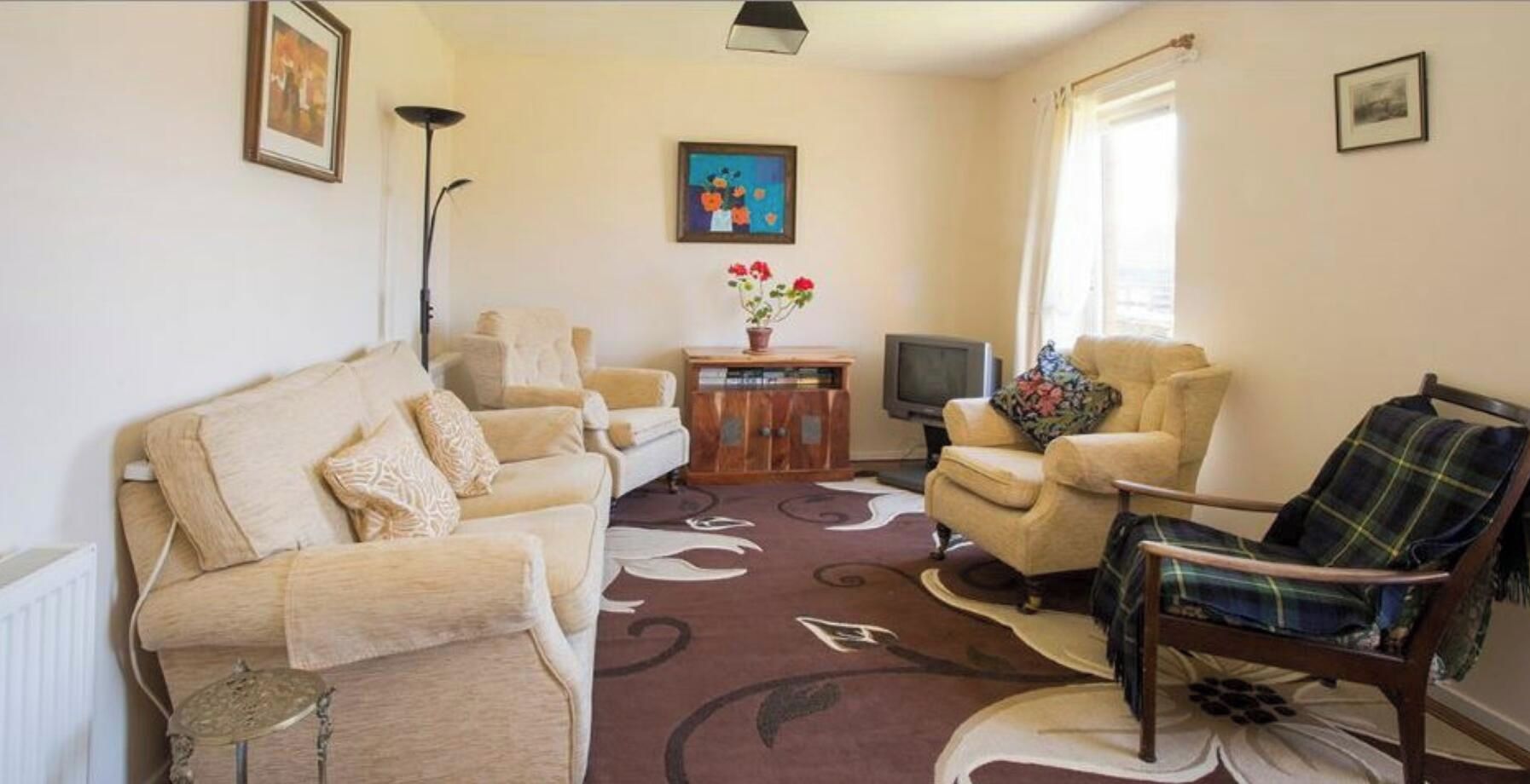 Un salon comprenant un canapé, des fauteuils, une table basse, un téléviseur et une cheminée.