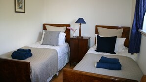 Una habitación de hotel con dos camas individuales, una mesita de noche con lámpara y un cuadro en la pared.