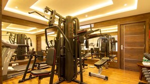A well-equipped gym with various exercise machines, a bench, and a mirrored wall. - Liverpool Hotels, Outer Ring Road, Marathahalli (Bengaluru)