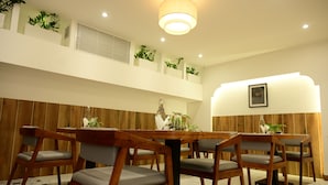 A dining area with a wooden table and chairs, a hanging light fixture, and potted plants on the wall. - Liverpool Hotels, Outer Ring Road, Marathahalli (Bengaluru)