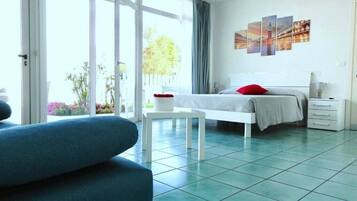 Une chambre d’hôtel moderne avec un lit, une chaise blanche, une petite table et une grande fenêtre.