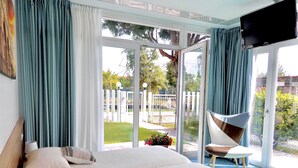 A bedroom with a large bed, a chair, and a TV. - Villa Marina (Venice)
