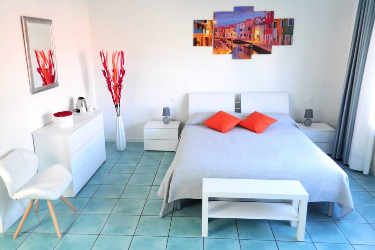 A modern bedroom with a bed, bedside tables, a chair, a dresser, and a wall art piece.