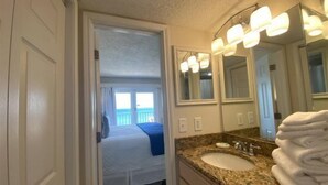 A hotel bathroom with a granite countertop, a sink, and a large mirror with lights. - Flash Sale! Surfside Shores 2/2 Sleeps 8 (Gulf Shores)