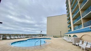A swimming pool with lounge chairs and a building with balconies. - Flash Sale! Surfside Shores 2/2 Sleeps 8 (Gulf Shores)