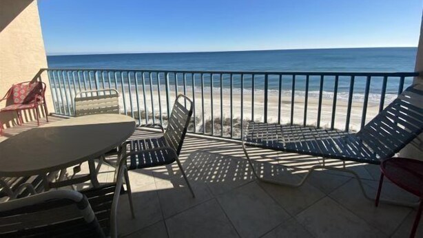A balcony with a table and chairs overlooking a beach. - Flash Sale! Surfside Shores 2/2 Sleeps 8 (Gulf Shores)
