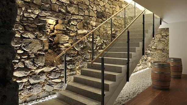 A staircase with stone walls and metal railings, leading to an upper level.