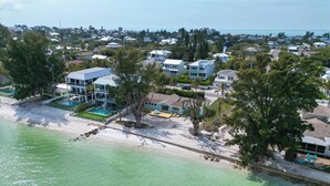 Et kystnære boligområde med huse, en strand og klart turkis vand.