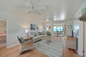 A spacious living room with a white ceiling fan, a sofa, wicker chairs, a coffee table, and a view of the ocean through a glass door. - Ocean Pearl: *Bay front *Ground-level *Gorgeous views (Anna Maria)