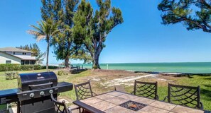 An outdoor patio with a grill, a table, and chairs. - Ocean Pearl: *Bay front *Ground-level *Gorgeous views (Anna Maria)