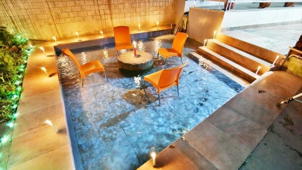 A heated outdoor pool area with four orange chairs and a central fire feature. - Hotel Rock Villa Dalhousie (Dalhousie)