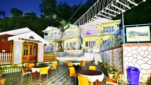 A food court with outdoor seating, a staircase connecting multiple levels, and a view of the surrounding area. - Hotel Rock Villa Dalhousie (Dalhousie)