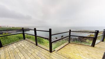 A wooden deck with a black railing overlooking a body of water.
