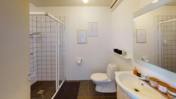 A bathroom with a shower, toilet, sink, and two framed pictures on the wall.