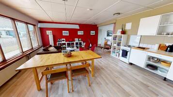 Una habitación amplia con una mesa de comedor de madera, paredes rojas y una zona de cocina con armarios blancos.