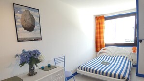 A bedroom with a bed, a dresser, a chair, a window with curtains, and a framed picture on the wall. - St-Lary-Soulan: Duplex T3, Sleeps 9, Fully Equipped with Balcony (Saint-Lary-Soulan)