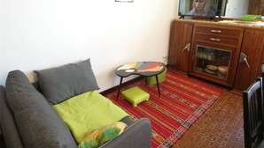 A living room with a sofa, a small table, a cabinet, and a television. - St-Lary-Soulan: Duplex T3, Sleeps 9, Fully Equipped with Balcony (Saint-Lary-Soulan)