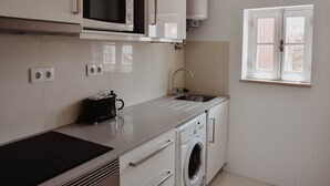 A compact kitchen with a microwave, toaster, sink, and washing machine. - Spacious, light-filled one-bedroom apartment (self check-in) (Coimbra)
