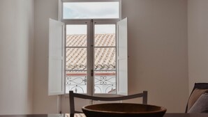 A dining area with a table, chairs, and a view through a window with an open door. - Spacious, light-filled one-bedroom apartment (self check-in) (Coimbra)