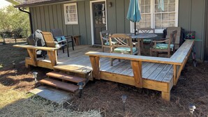 Eine Holzterrasse mit Gartenmöbeln, darunter ein Tisch und Stühle, sowie ein überdachter Sitzbereich mit Sonnenschirm.