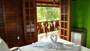 Una habitación de madera con una cama, una pantalla verde y vistas a árboles.