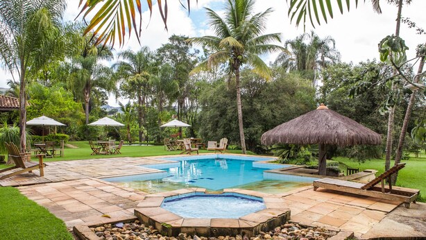 Un área de piscina con un jacuzzi, sillas de descanso y sombrillas.