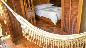 Una hamaca con reposacabezas de madera y una cama con ropa de cama blanca.