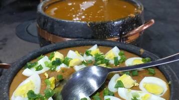 Buffet com diversos pratos, incluindo uma tigela de sopa decorada com cebolinha picada e ovos cozidos.