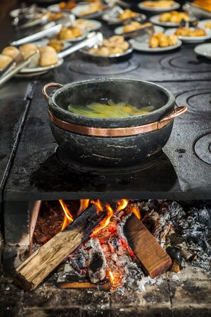 Une cuisine traditionnelle avec une casserole sur la cuisinière, entourée de divers aliments disposés sur des assiettes.