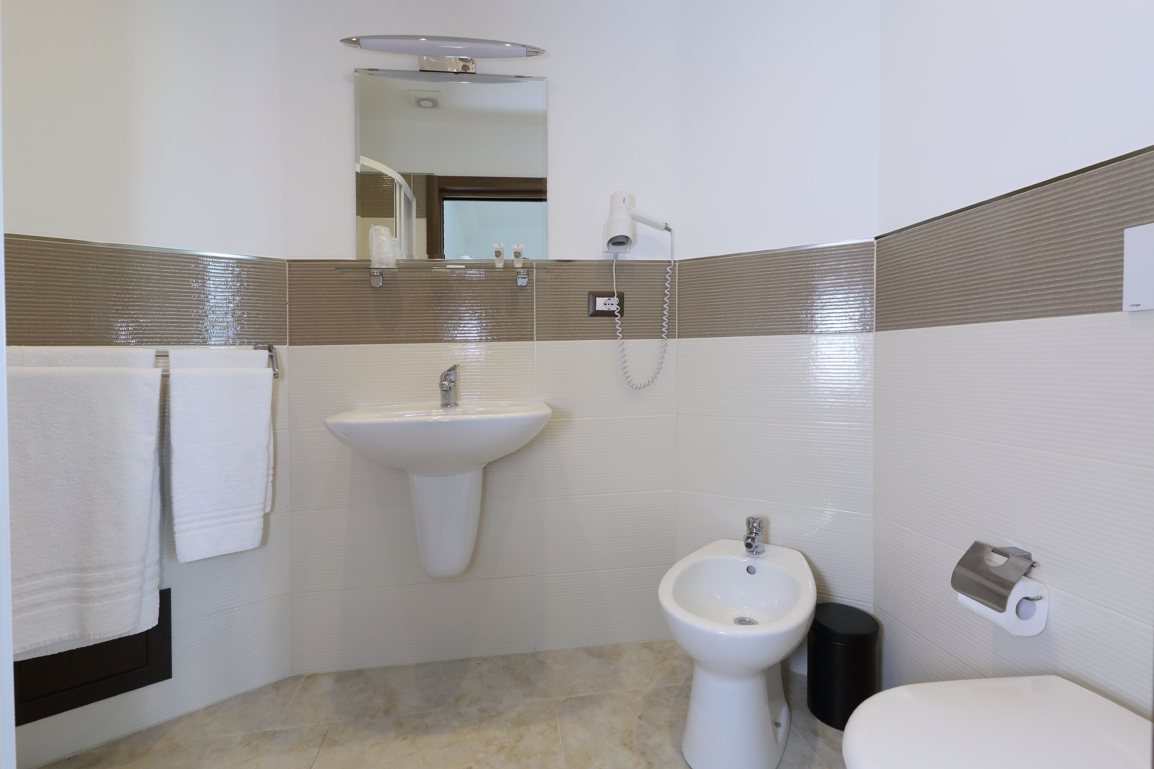 A bathroom with a sink, bidet, and toilet.