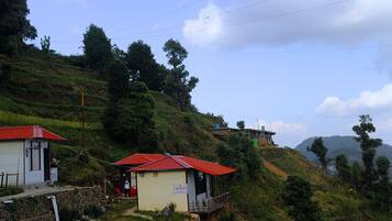 A hillside with small buildings, including a guesthouse with a red roof and a sign indicating it is a guesthouse.