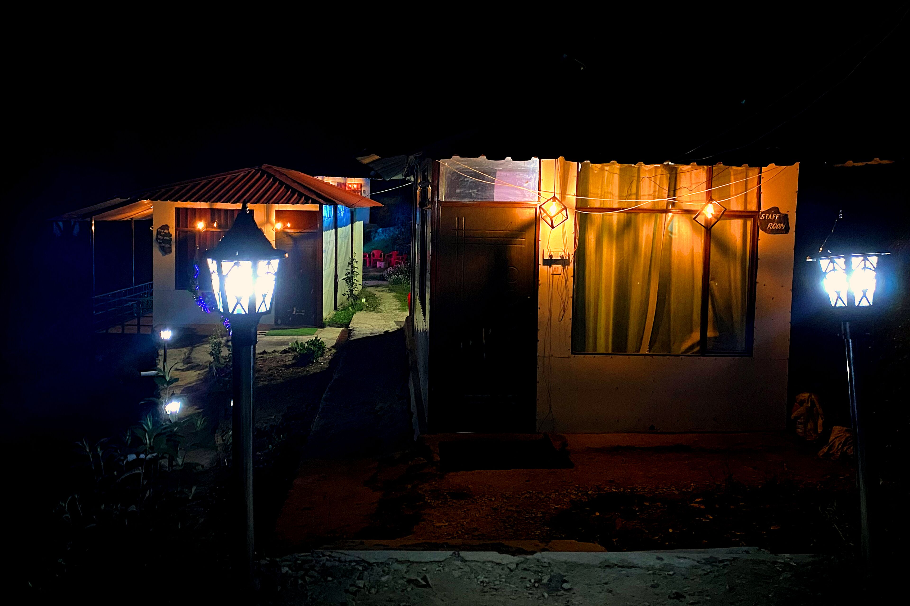 A small, dimly lit building with a sign reading "STAFF ROOM" and a window with curtains.