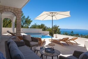 A rooftop pool area with lounge chairs, a table, and a view of the sea. - Villa Nature Beauty with Heated Pool (Makarska)