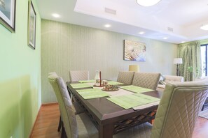 A dining area with a long table, cushioned chairs, and a decorative wall piece. - OYO Home 300 2BHK Al Waleed Paradise JLT (Dubai)