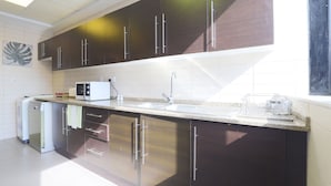 A modern kitchen with dark cabinets, a double sink, and a dishwasher. - OYO Home 300 2BHK Al Waleed Paradise JLT (Dubai)