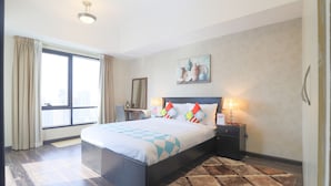 A modern hotel room with a large bed, a nightstand, a desk, and a window with curtains. - OYO Home 300 2BHK Al Waleed Paradise JLT (Dubai)