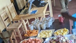 Een tafel met diverse etenswaren zoals brood, eieren, bananen en gesneden fruit.
