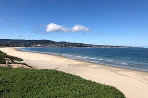 A beach with a clear view of the ocean, a sandy shore, and a distant town.
