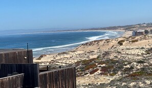 Une vue sur la côte, avec une terrasse en bois donnant sur la plage et l’océan.