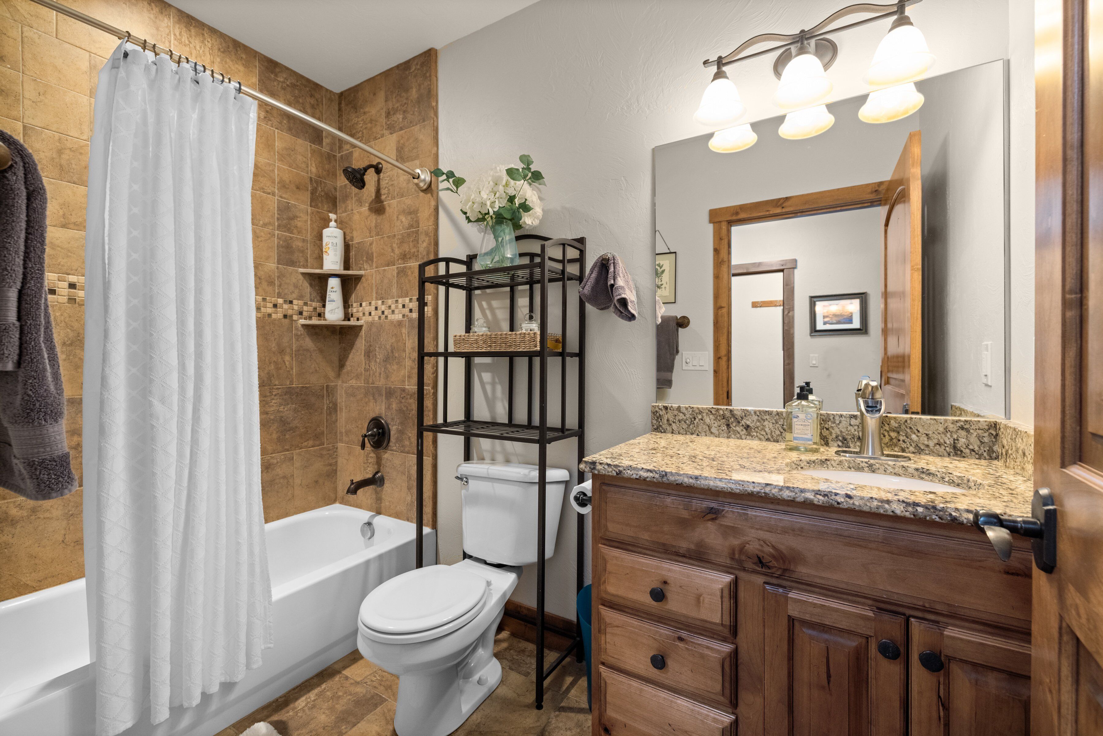A bathroom with a bathtub, toilet, and vanity with a mirror.