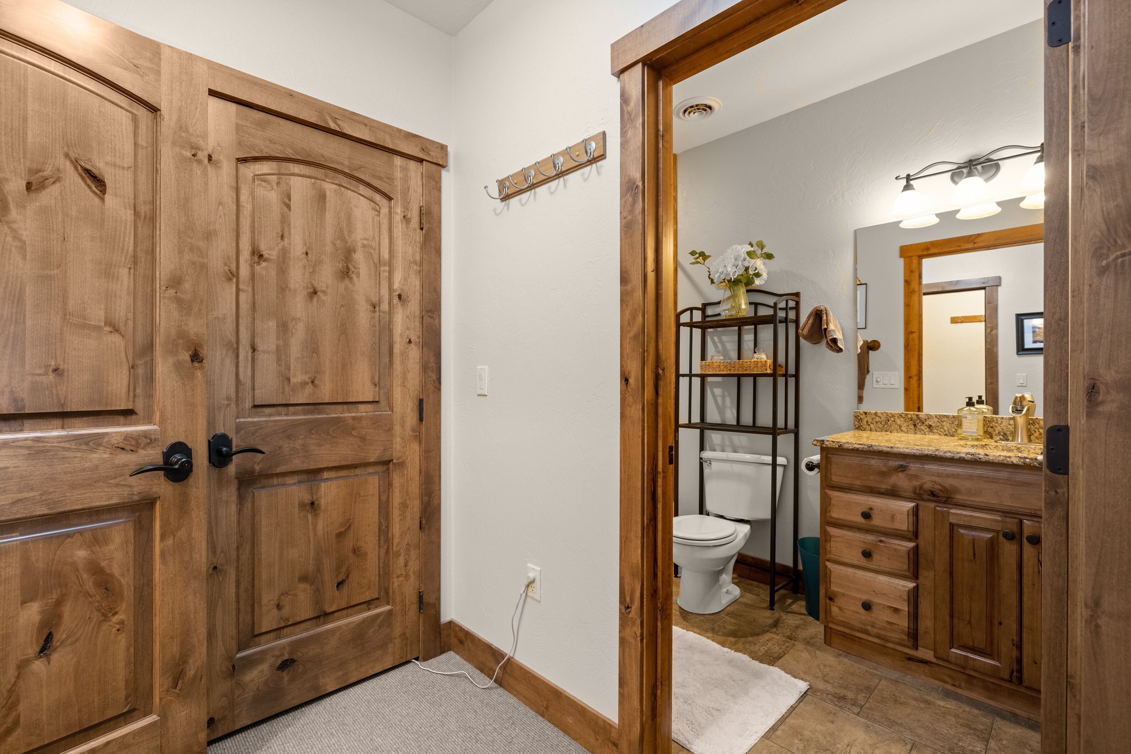 A bathroom with wooden cabinets, a toilet, and a sink with a mirror.