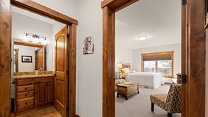 A bedroom with a bed, a chair, and a nightstand. - Incredible Whitefish Mountain Ski and summer baselodge! Underground parking and close ski access (Whitefish)