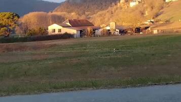 Un paysage rural avec une route, des bâtiments et une colline sur laquelle se trouve une église.