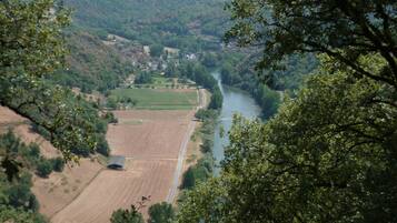 Un río serpentea por un valle con campos y un pequeño asentamiento a lo lejos.