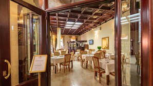 Un restaurante con mesas y sillas de madera, una zona de bar y un candelabro.