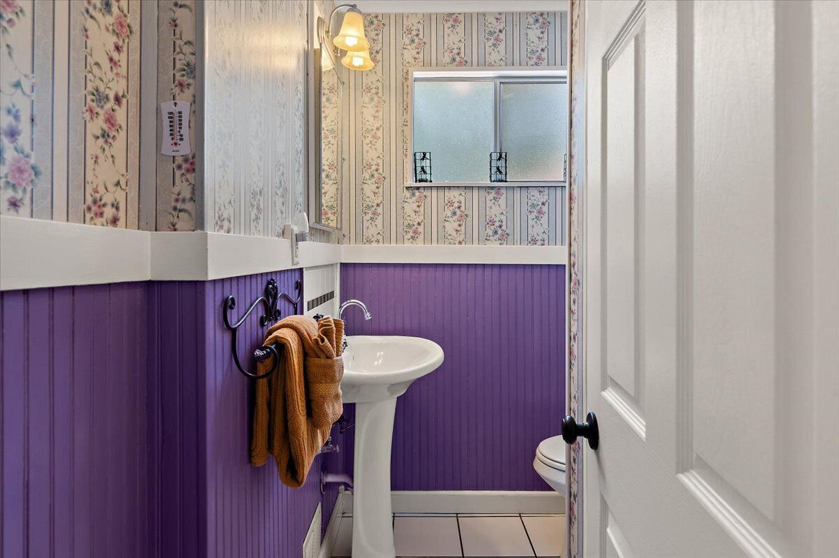 A bathroom with a purple wall, a white sink, and a window with frosted glass.