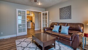 A living room with a brown leather sofa, a wooden coffee table, and a patterned rug. - Cozy and Stylish Home (Boise)